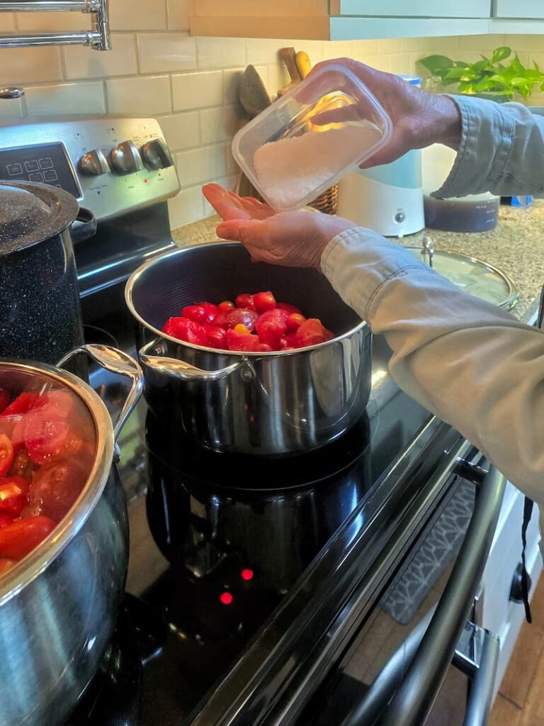 adding salt to pans of tomatoes during the canning process