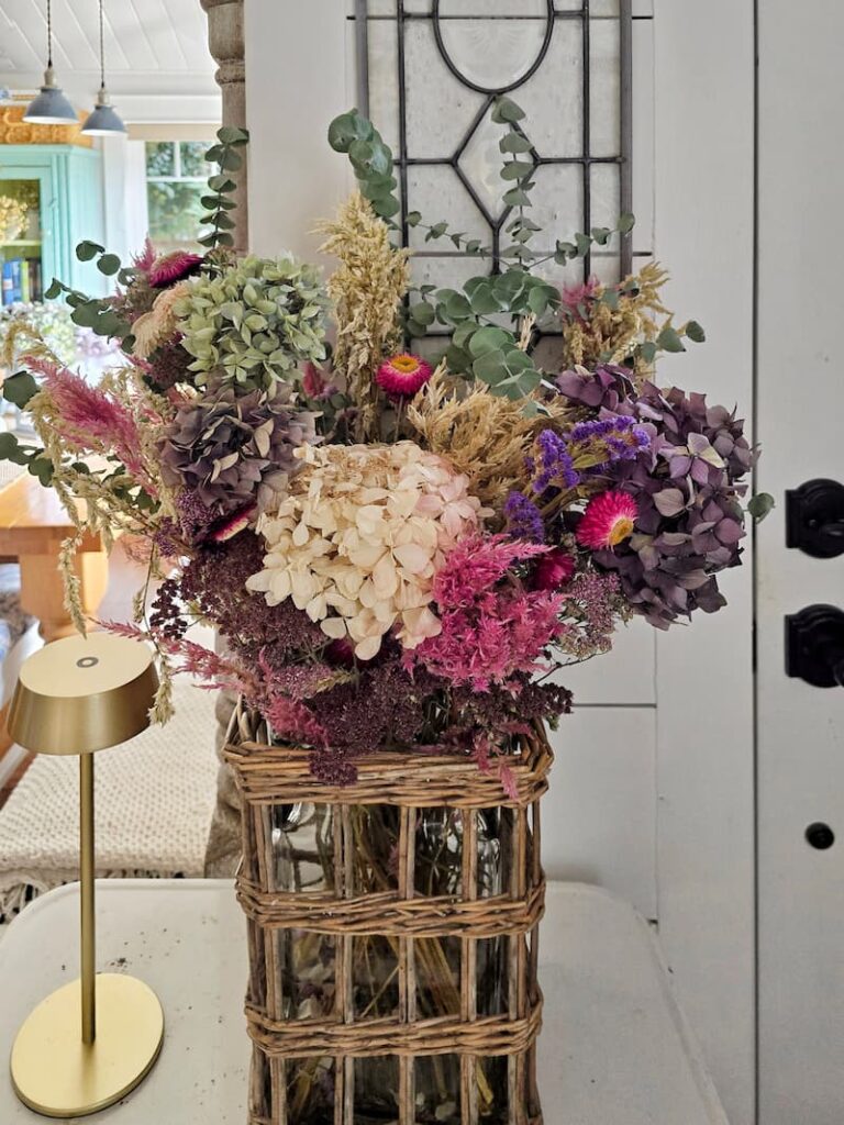 wicker and glass vase of dried flowers from the garden