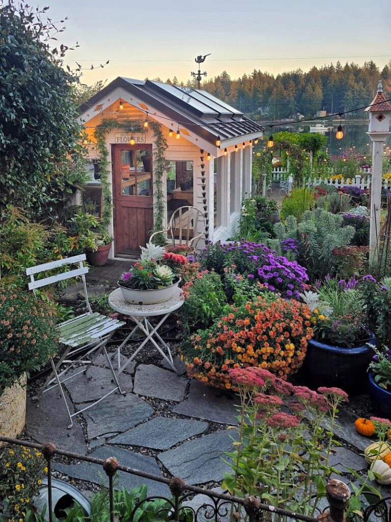 Stone patio with fall containers leading to the greenhouse