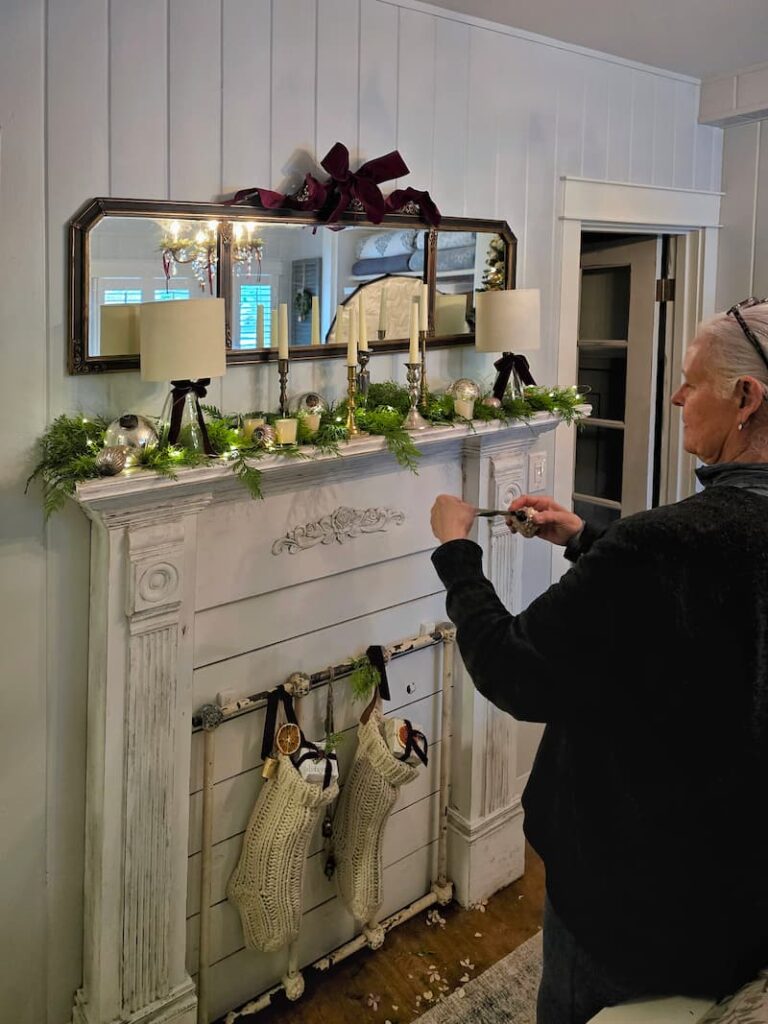 Stylist decorating a bedroom mantel for a Christmas magazine shoot
