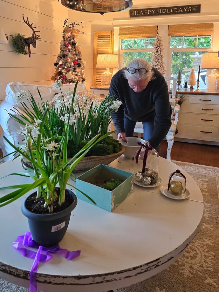 Magazine stylist arranging a Christmas coffee table vignette in a cottage living room