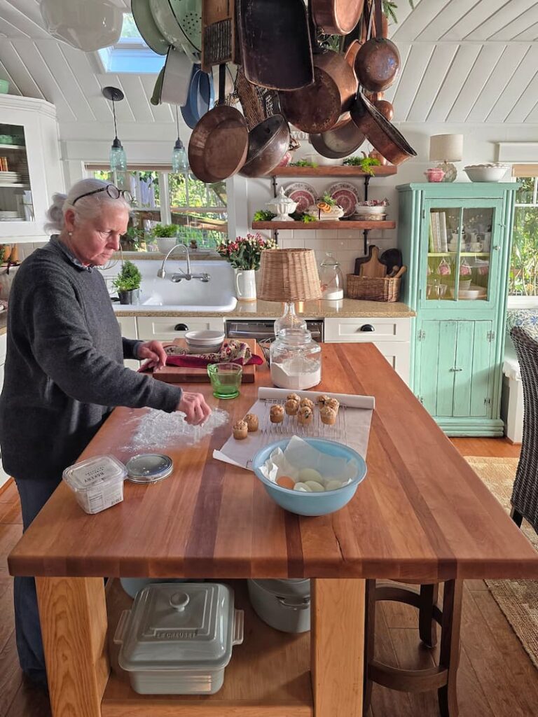 Stylist arranging Christmas decor on a cottage kitchen island